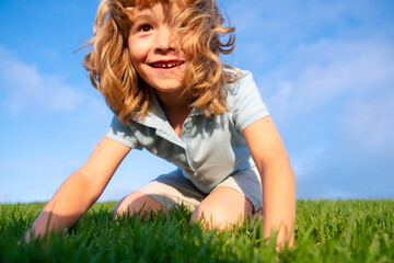 Fototapeta premium Portrait of a excited little boy in the park. Funny little boy playing in garden backyard laughing and having fun. Summer outdoors activity for kids. Child with a cute expression face.
