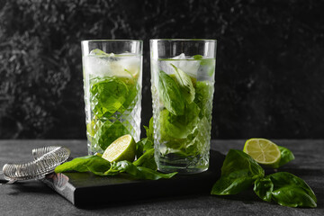 Glasses of lemonade with basil on dark background