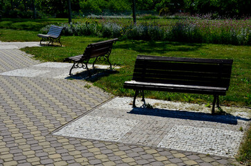 in the park. solid concrete bench with a log as a backrest. perennial flower beds and lawns in the...