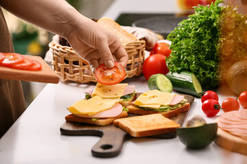 Woman preparing tasty sandwiches in kitchen