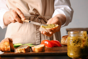 Woman preparing tasty sandwiches on table
