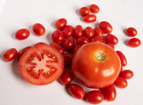 jitomate partido con jitomate entero sobre jitomates cherry, con fondo blanco 