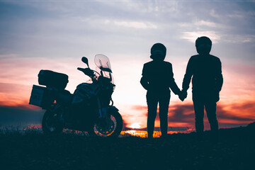 Silhouette of lover couple in sunset with motorcycle in sunset.