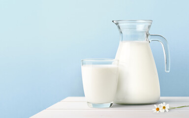 Glass and Jug of fresh milk on white wooden table. - obrazy, fototapety, plakaty