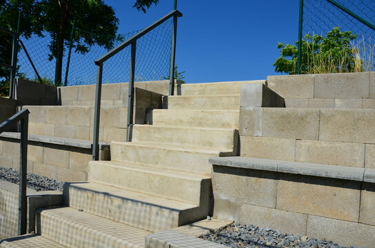 Outdoor playground for ball games. high barriers fencing protect spectators on a concrete tribune in the shape of stairs. Amphireeater from which we watch the match