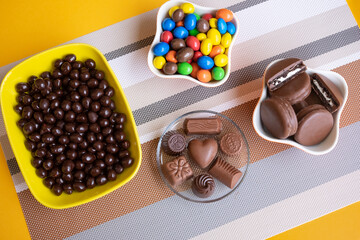 Bowls filled with different kinds of brown and colorful chocolates of different colors and shapes