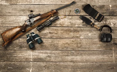 Foto op Plexiglas Hunting equipment on old wooden background including rifle, knife, binoculars and cartridges © fotofabrika