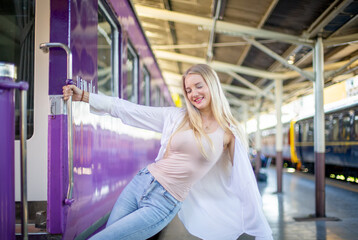 young woman waiting in vintage train, relaxed and carefree at the station platform in Bangkok, Thailand before catching a train. Travel photography. Lifestyle.