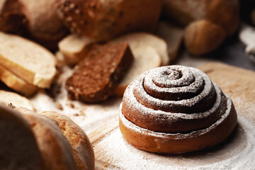 Fresh cinnamon bun roll with sugar powder on wooden board
