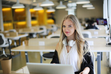 Smiling woman using laptop in work place for small businesses looking to engage audiences and scale content creation can adopt new marketing technology in workspace. Freelancer concept.