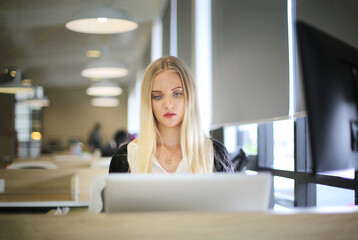 Smiling woman using laptop in work place for small businesses looking to engage audiences and scale content creation can adopt new marketing technology in workspace. Freelancer concept.