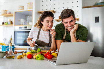 Happy young couple preparing food in kitchen at home