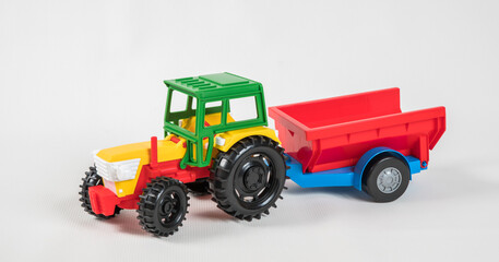 Plastic toy multicolored cars isolated on white background. Tractor with a trailer.