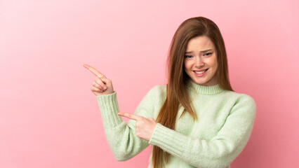 Teenager girl over isolated pink background frightened and pointing to the side