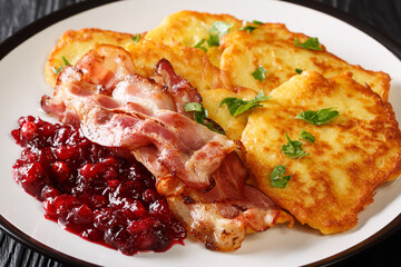 Scandinavian potato pancakes served with lingonberry jam and bacon close-up on a plate on the table. horizontal