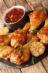 grilled chicken drumstick with garlic and rosemary close-up on a slate board on the table. Vertical