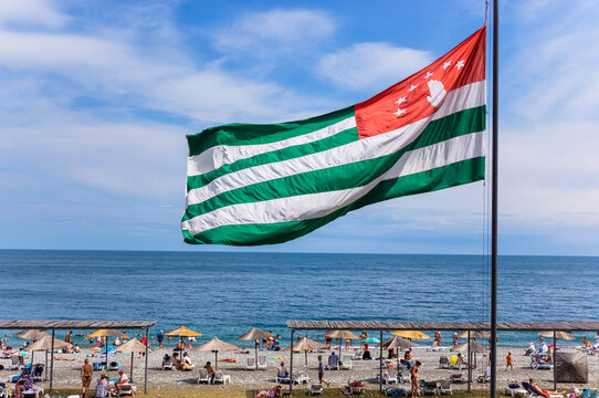 Sea landscape with flagpole and Abkhaz flag on the sky background.