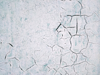 The texture of the painted wall in white and turquoise, which was covered with large black cracks. Concept background, texture