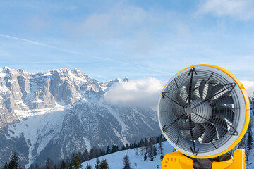 View of the yellow snow cannon against the backdrop of snow-capped mountains. Landscape, industry, sports concept