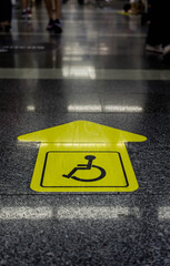 yellow sticker in the form of an arrow on the airport floor, indicating the direction for people with disabilities