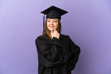 Young university graduate over isolated purple background looking to the side and smiling
