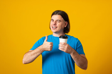 Man holding coffee to go cup showing thumb up. Coffee take away cup in hands.