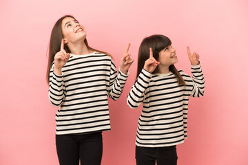 Little sisters girls isolated on pink background pointing with the index finger a great idea
