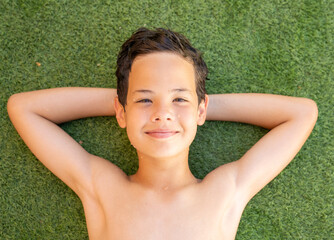 Happy boy lying down on the grass with thumb up. Summer season. © Danko