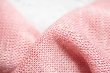 Knitted pink fabric close-up. The folds in the fabric, the weave structure is visible, two layers of fabric one after the other. 