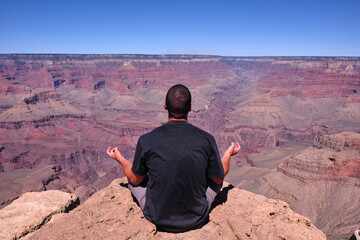 man meditating in the lotus flower position overlooking the Grand Canyon, Arizona, USA