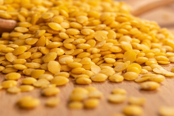 Yellow raw lentils in a wooden spoon