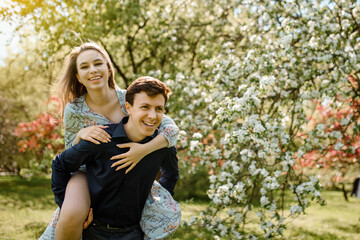 Fototapeta premium young beautiful couple having fun in a blossoming cherry flowers tree.