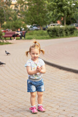Naklejka premium Little girl toddler runs after pigeons. Summertime