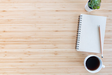 flat lay composition with notebook, pen, coffee, plant, laptop on wood background. top view