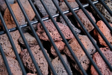 Lava stone for grilling. The view through the blurred grill grate. Close-up. Selective focus.