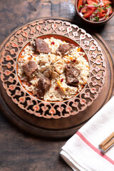The concept of oriental cuisine. Traditional asian dish - pilaf from rice, vegetables and meat in a plate on a wooden table. background image. top view, copy space, flat lay