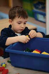 One kid choose parts of robotic electric toys for his age of four to build robots at robotics school lesson.