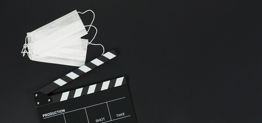 Black clapper board or movie slate and face mask on black background.it use in video production and...