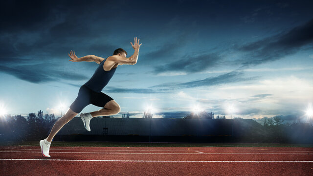 One professional male runner, jogger training at stadium in evening. Caucasian fit athlete practicing, Concept of sport, healthy lifestyle.