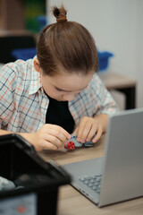Fototapeta na wymiar Boy using a laptop to program assembled robot from plastic bricks. STEM Education for kids.