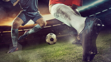 Two male soccer, football players dribbling ball at the stadium during sport match on dark sky background.