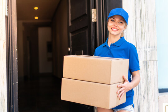 Young delivery woman at outdoors holding boxes with happy expression