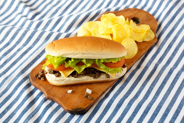 Homemade Chopped Beef Sandwich with Potato Chips on a rustic wooden board, low angle view.