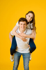 young happy couple man and woman in white t-shirts smiling and laughing on a yellow background..
