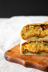 Homemade Breakfast Egg Burrito with Avocado and Bacon on a rustic wooden board, side view. Copy space.