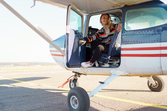 Young fashionable woman pilot ready to fly, start training, in small airplane. Learning process.