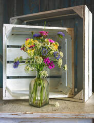 Still life with a small bouquet of meadow daisies on a background of white wooden boxes