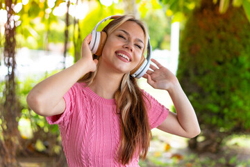 Young pretty woman at outdoors listening music and singing
