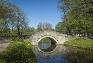 Fototapeta na wymiar An ancient bridge over the river in the city park