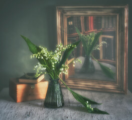 A small spring bouquet is reflected in an old and crooked mirror in a wooden frame.